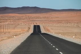 free black road in red desert, namibia