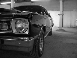 black and white photo of the side of the shiny car near the wall