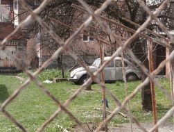 old car, volkswagen beetle at house behing wire fence