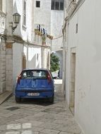 blue car on a narrow street