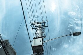 telephone poles and street lamp at the background of the cloudy sky