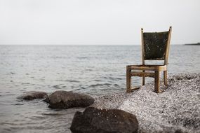 armchair stands on the beach near the water