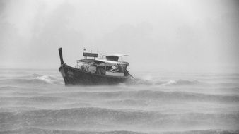 landscape of boat floating in stormy ocean