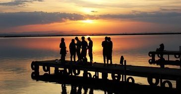 People on a lake bank at the sunset