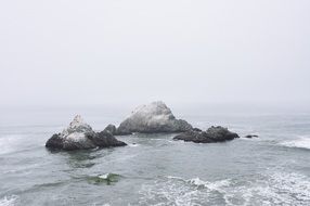 rocks in sea on foggy weather