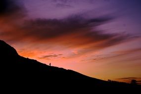 silhouette of a man on a slope against a sunset