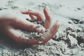 wet sand in young person’s hand on beach