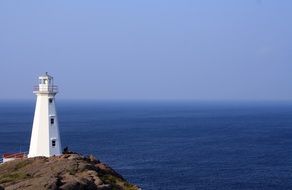 lighthouse on rock at blue seascape