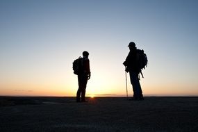 silhouettes of two hikers at sunset at twilight