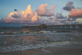 pier along coastline and bright clouds