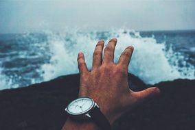 hands with watch by the ocean