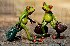 two toy frogs with suitcases
