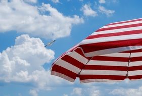 red and white striped beach umbrella at sky with fluffy clouds