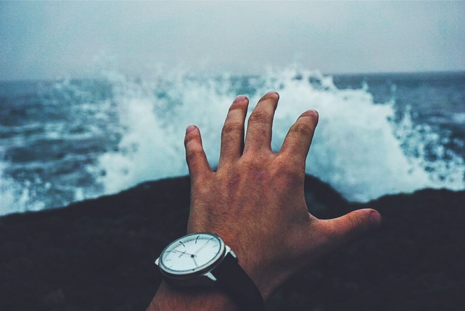 hands with watch by the ocean