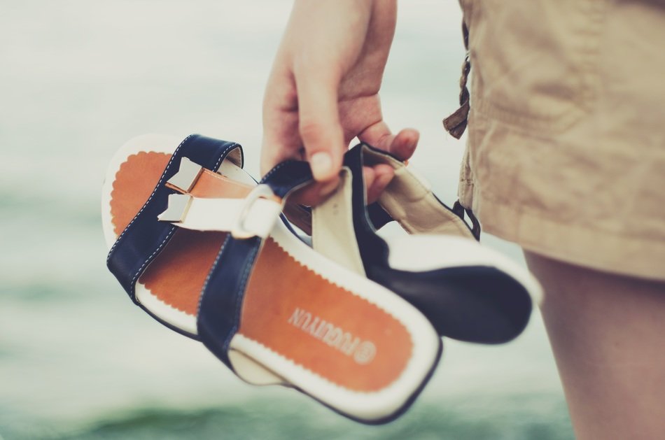 Person holding blue, orange and white sea slippers