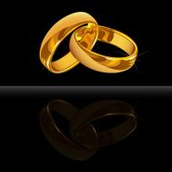 Gold wedding rings on black background with reflection