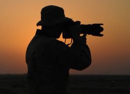 silhouette of a man with a camera at sunset