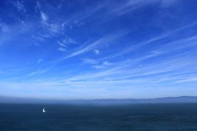 white sailing ship on the horizon in the ocean