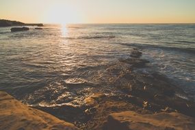 the sun's rays over the rocky shore of the ocean