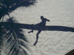 shadow in the sand in the form of a man on a tree trunk