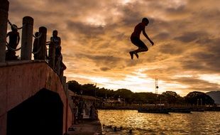 Children jumping from the bridge at sunset