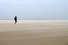 man in a black suit on the shore of the North Sea
