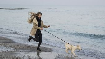 mistress with a puppy run along the sandy beach