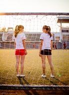 two young women in sports uniform behind gates
