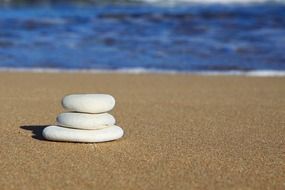 three stacked stones on the sand by the ocean