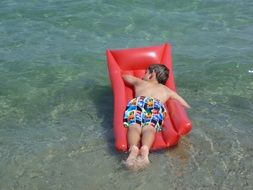 child on an inflatable mattress on the beach