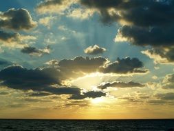 sun rays in dark clouds over the ocean