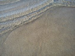 clear waves splashing on grey sand beach