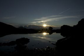 sunset behind the clouds is reflected in the water