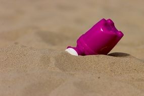 purple watering can in sand