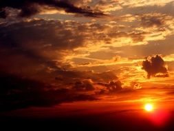 View in the distance sun at sunset amid the clouds