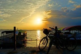 bicycle stands on the seashore at sunset