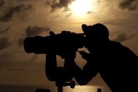 man looking at naval binoculars