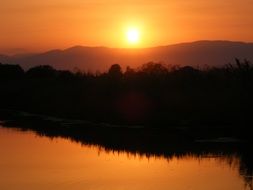 sunset sky mirroring on forested lake