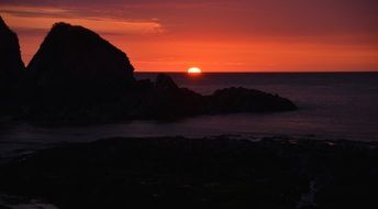 dark rocks and sea under red sunset sky, sunset uk, england, devon