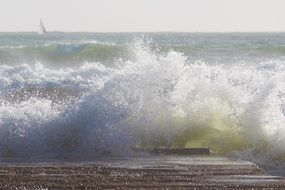 foamy ocean waves crushing on pier