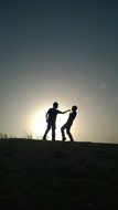 silhouettes of two people at sunset