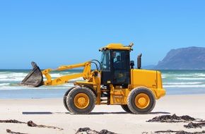 excavator on the beach removes trash
