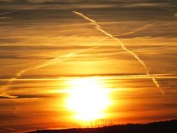 bright sunset in the sky with contrails