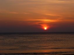 distant view of the setting red sun above the sea