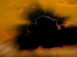 orange sky behind dark cloud at sunset