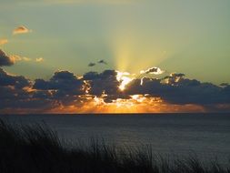 gorgeous sunset on sea with sun beams through dark clouds, germany, sylt
