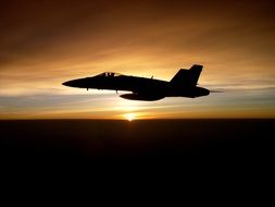 Silhouette of military aircraft on sunset background