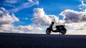 scooter on the road against the blue sky with clouds