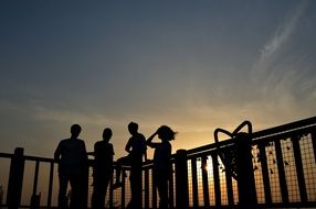people near fence sunset view