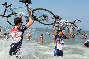 men with bicycles in the ocean